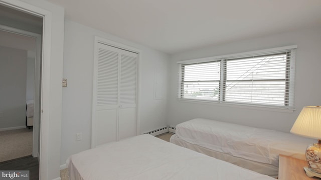 bedroom with baseboard heating and a closet