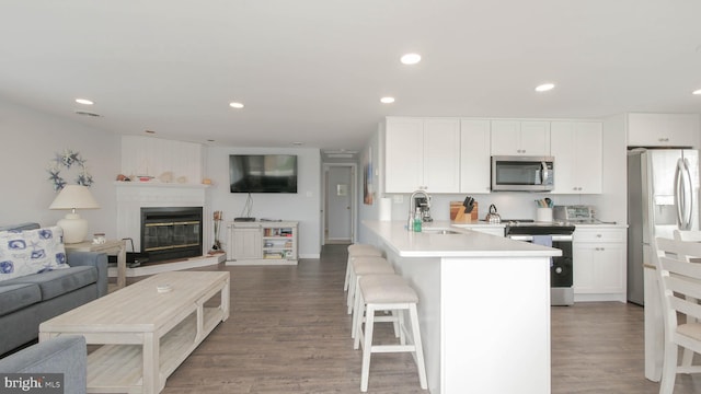 kitchen with white cabinetry, sink, dark wood-type flooring, kitchen peninsula, and appliances with stainless steel finishes