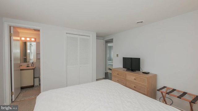 carpeted bedroom featuring ensuite bathroom and a closet