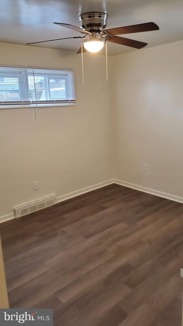 unfurnished room featuring dark hardwood / wood-style flooring, a healthy amount of sunlight, and a baseboard heating unit