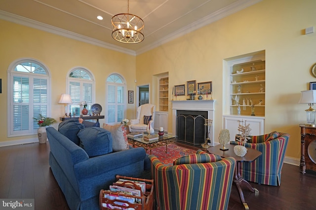 living room with crown molding, built in features, dark wood-type flooring, and an inviting chandelier