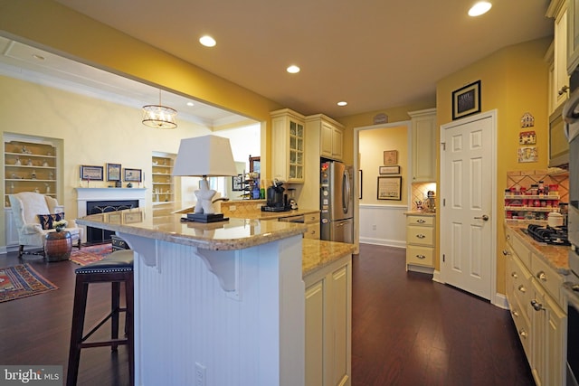 kitchen with hanging light fixtures, stainless steel appliances, light stone counters, dark hardwood / wood-style floors, and a breakfast bar area