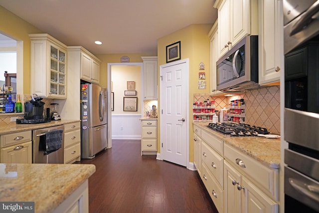 kitchen with backsplash, dark hardwood / wood-style floors, light stone countertops, and stainless steel appliances