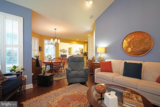 living room with lofted ceiling, a wealth of natural light, a chandelier, and dark hardwood / wood-style floors