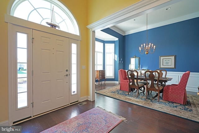 foyer featuring dark hardwood / wood-style flooring, crown molding, and an inviting chandelier