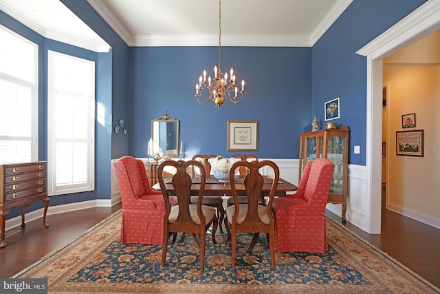 dining area with ornamental molding, an inviting chandelier, and dark wood-type flooring