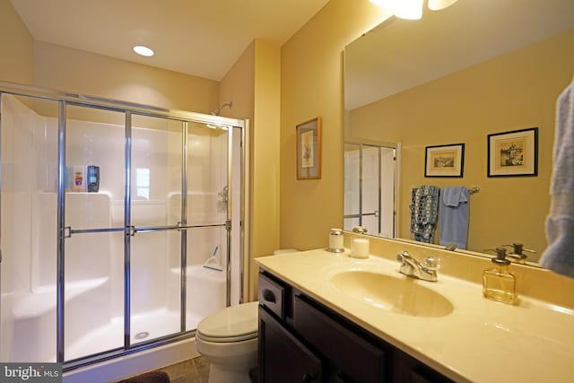 bathroom with tile patterned floors, vanity, toilet, and a shower with door