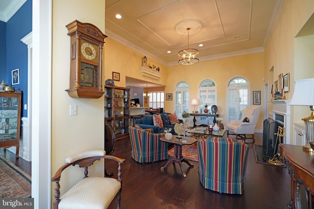 living room with hardwood / wood-style flooring, a healthy amount of sunlight, crown molding, and an inviting chandelier