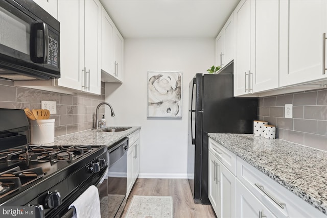 kitchen with light stone countertops, sink, white cabinetry, and black appliances