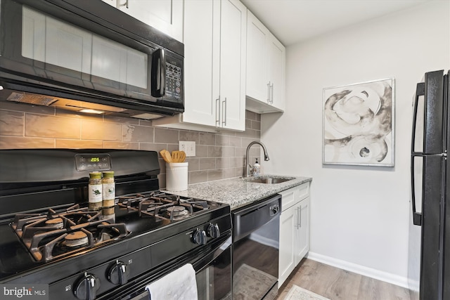 kitchen with black appliances, light hardwood / wood-style floors, white cabinets, and sink