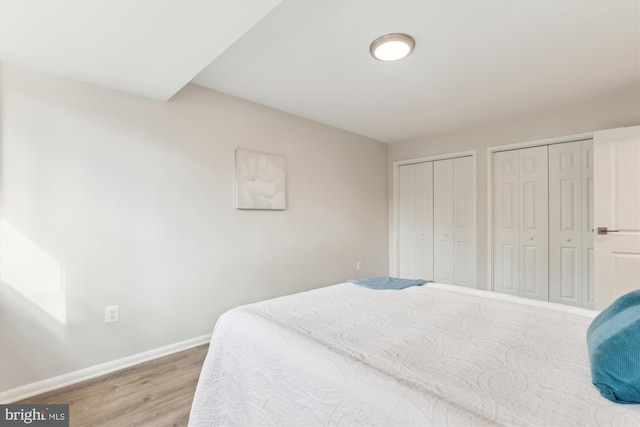 bedroom featuring wood-type flooring and two closets