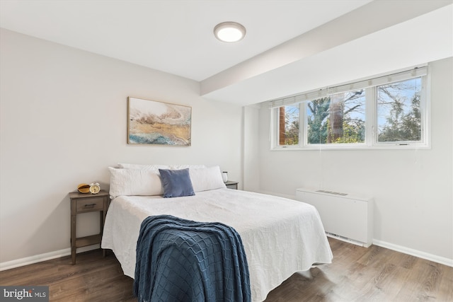 bedroom with radiator heating unit and dark wood-type flooring