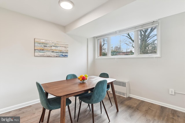 dining space featuring radiator and hardwood / wood-style flooring