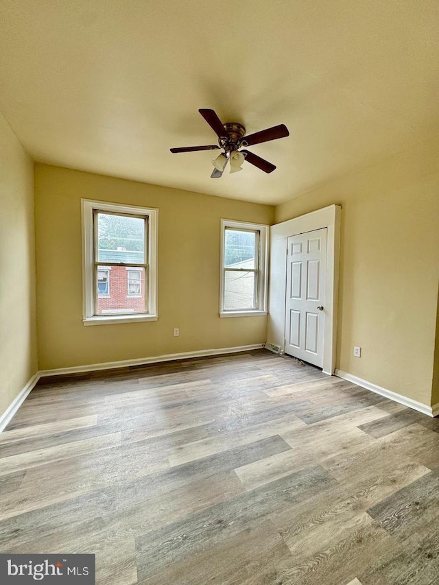 unfurnished bedroom with ceiling fan, light hardwood / wood-style floors, and multiple windows