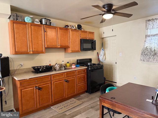 kitchen with black appliances, ceiling fan, sink, and light hardwood / wood-style flooring