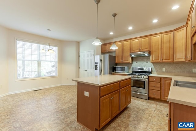 kitchen featuring a center island, stainless steel appliances, a notable chandelier, backsplash, and decorative light fixtures