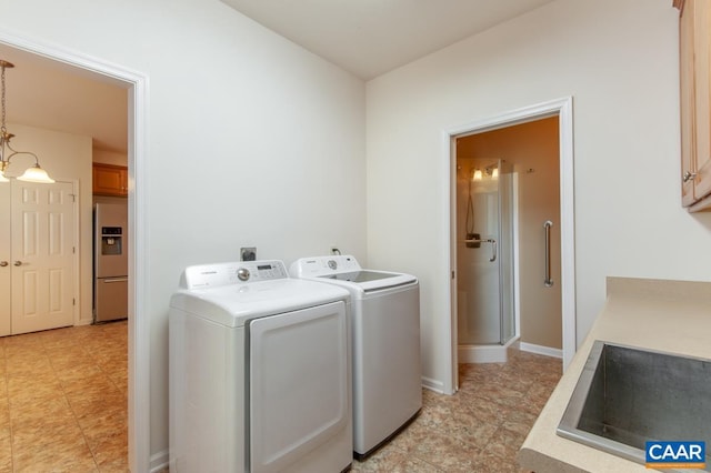 washroom with a notable chandelier, washer and dryer, cabinets, and sink