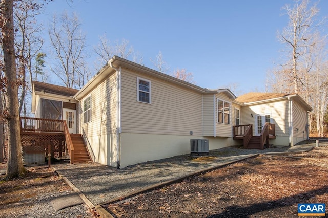 exterior space with a sunroom, a wooden deck, and central AC