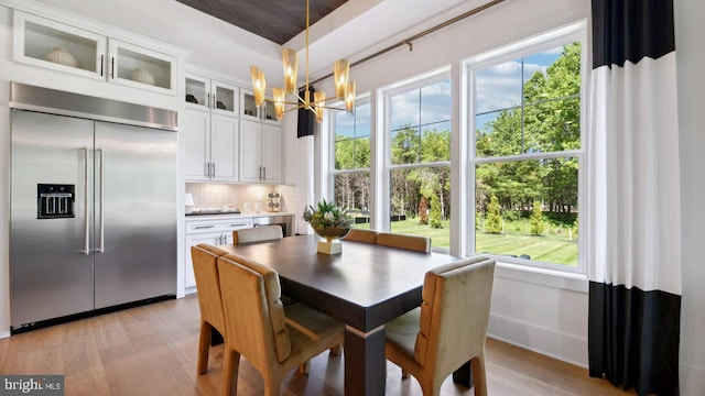 dining area with a wealth of natural light, an inviting chandelier, and light wood-type flooring