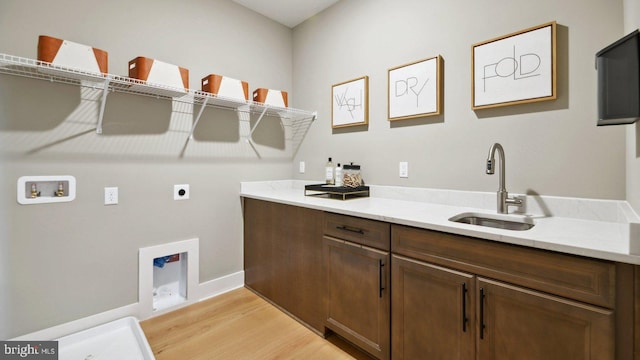 clothes washing area with hookup for an electric dryer, hookup for a washing machine, cabinets, sink, and light hardwood / wood-style flooring