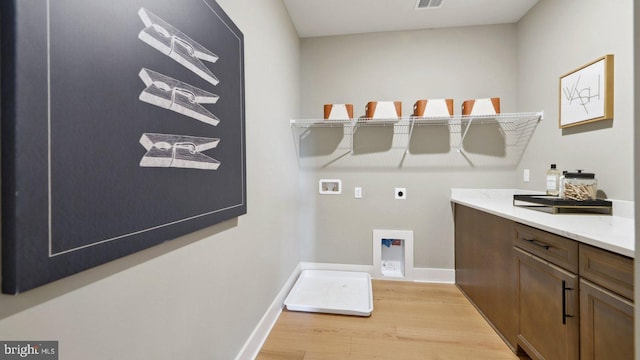 laundry area with electric dryer hookup, cabinets, light hardwood / wood-style floors, and washer hookup