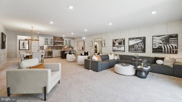 living room with light colored carpet, wine cooler, and a chandelier