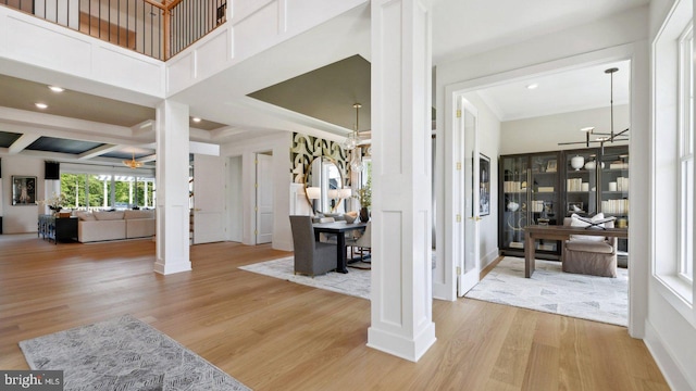 foyer featuring beamed ceiling, decorative columns, light hardwood / wood-style flooring, and crown molding