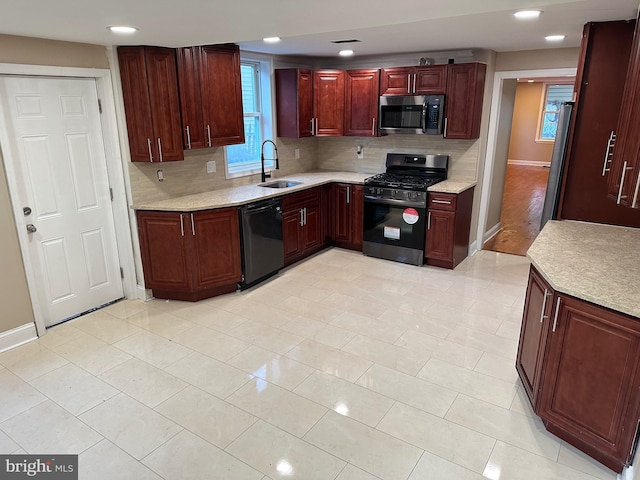 kitchen with appliances with stainless steel finishes, backsplash, light tile patterned floors, and sink