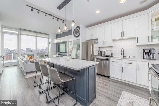 kitchen with pendant lighting, white cabinetry, sink, and stainless steel appliances