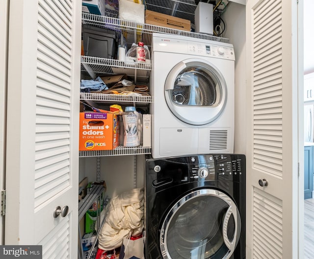 clothes washing area with wood-type flooring and stacked washer and dryer