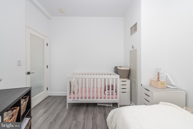 bedroom with wood-type flooring and a nursery area