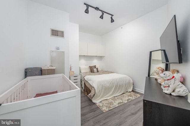 bedroom featuring rail lighting and dark wood-type flooring