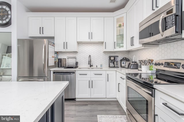 kitchen featuring white cabinets, appliances with stainless steel finishes, light hardwood / wood-style floors, and sink