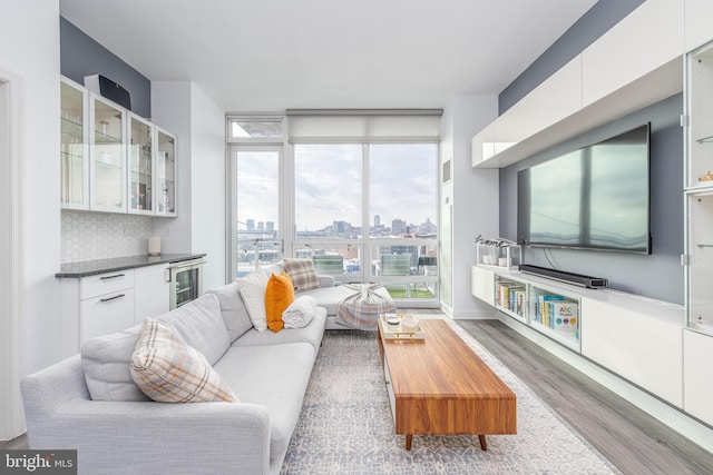 living room featuring wood-type flooring, plenty of natural light, and beverage cooler