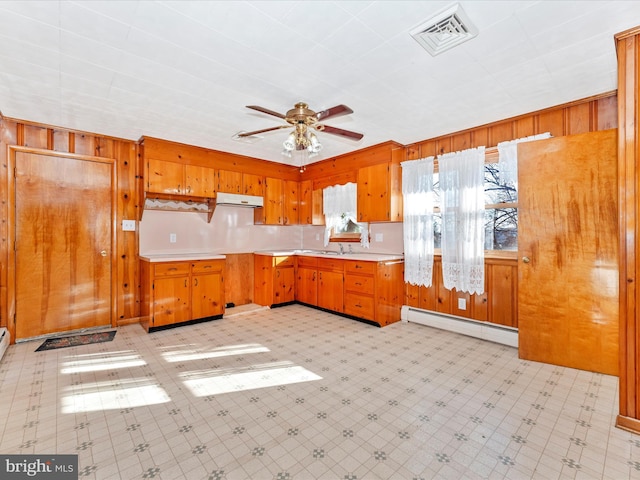 kitchen with ceiling fan, wood walls, sink, and a baseboard radiator