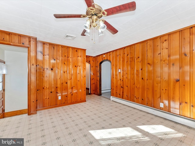 empty room featuring a baseboard radiator, ceiling fan, and wood walls