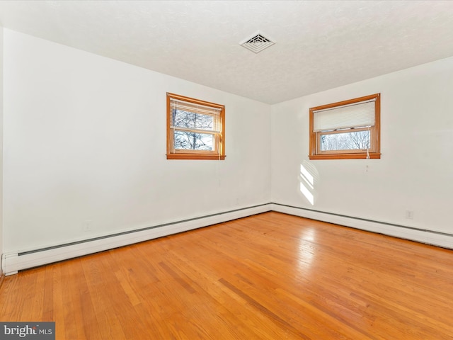 unfurnished room featuring plenty of natural light, hardwood / wood-style floors, and a textured ceiling