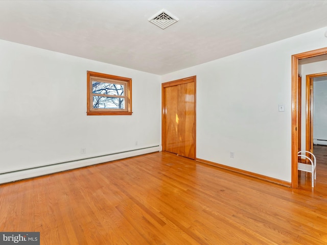 empty room with light hardwood / wood-style floors and a baseboard radiator