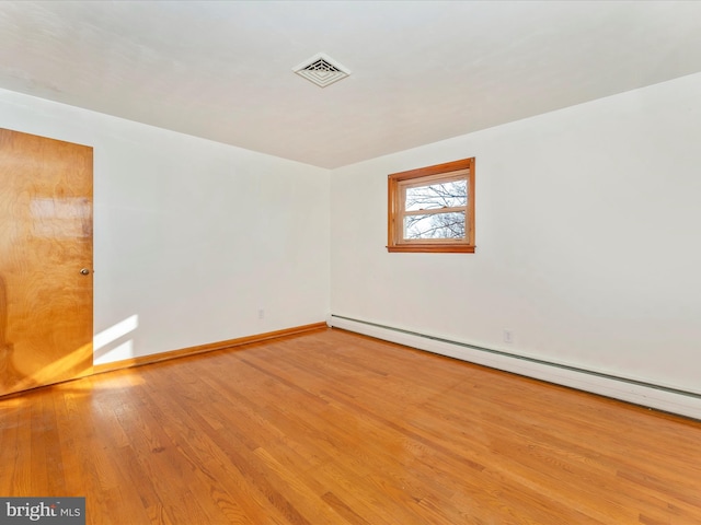 spare room featuring light wood-type flooring and a baseboard radiator