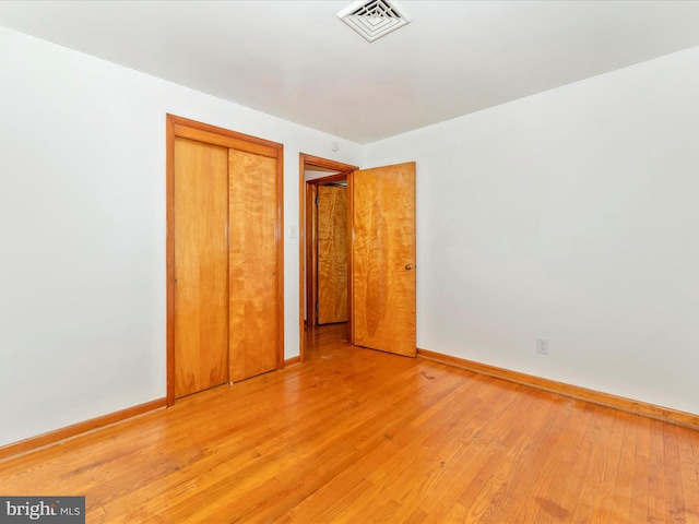 unfurnished bedroom with light hardwood / wood-style flooring and a closet