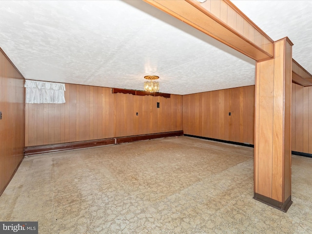 additional living space featuring wooden walls and a textured ceiling