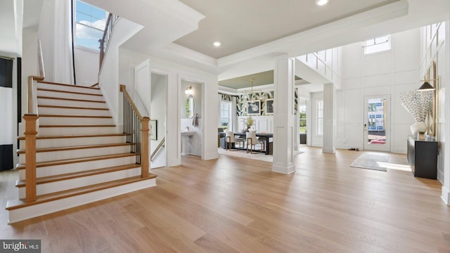 foyer entrance featuring plenty of natural light, a raised ceiling, a chandelier, and light hardwood / wood-style flooring