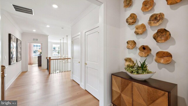 corridor featuring light wood-type flooring and crown molding