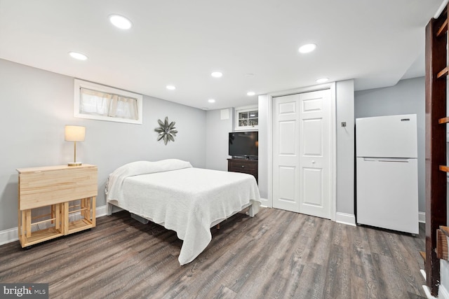 bedroom with a closet, dark hardwood / wood-style flooring, and white fridge