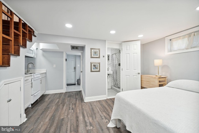 bedroom featuring dark hardwood / wood-style flooring, ensuite bath, and sink