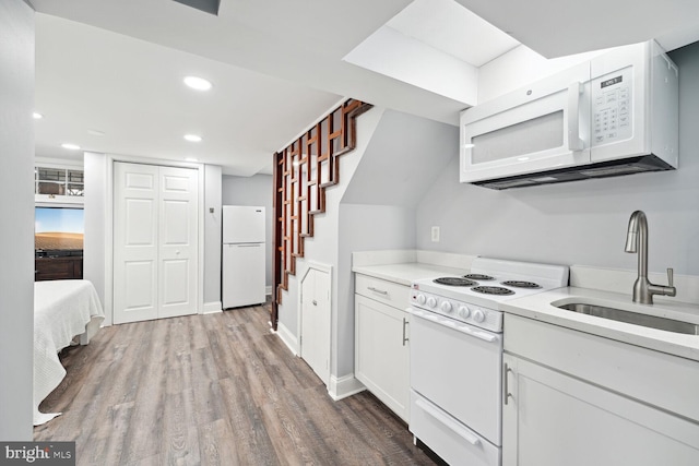 kitchen with light hardwood / wood-style floors, white cabinetry, white appliances, and sink