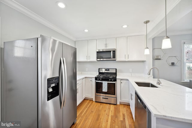 kitchen featuring white cabinets, sink, hanging light fixtures, light wood-type flooring, and stainless steel appliances