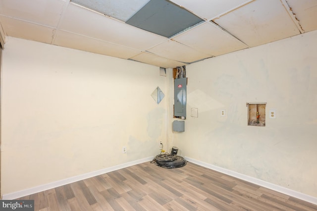 basement with a drop ceiling, electric panel, and hardwood / wood-style flooring