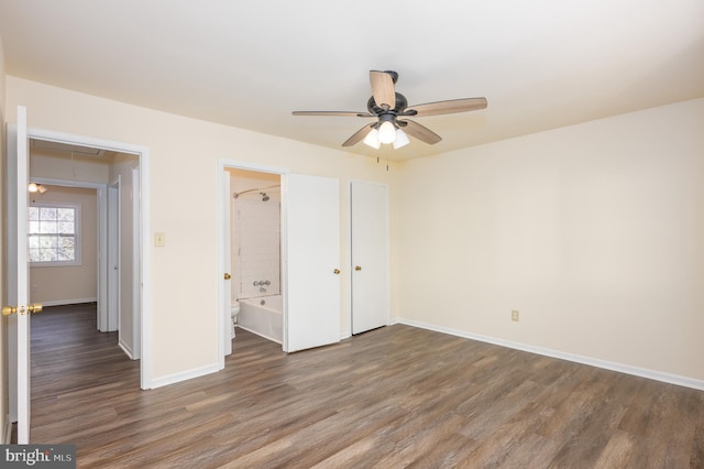 unfurnished bedroom featuring ensuite bath, ceiling fan, and dark hardwood / wood-style floors