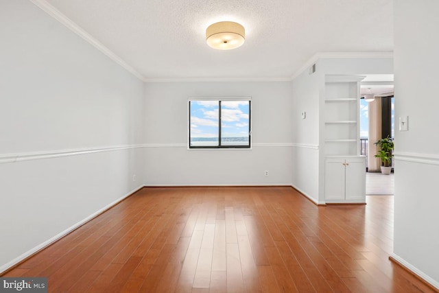 unfurnished room featuring a textured ceiling, baseboards, and wood finished floors